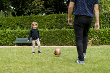 Father and son playing football in park - MAUF02081