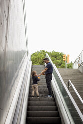 Vater und Sohn mit Softdrinks auf der Rolltreppe - MAUF02083