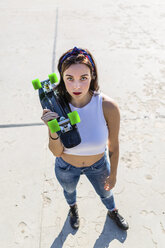 Porträt einer jungen Frau, die ein Skateboard hält - MGIF00264