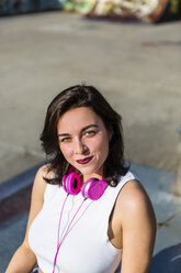 Portrait of smiling young woman with headphones in the city - MGIF00280