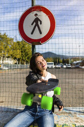 Portrait of smiling young woman holding skateboard - MGIF00281