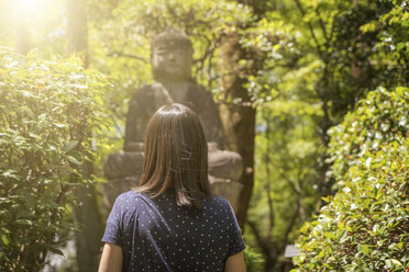 Frau betrachtet Buddha-Statue an einem sonnigen Tag - EPF00512