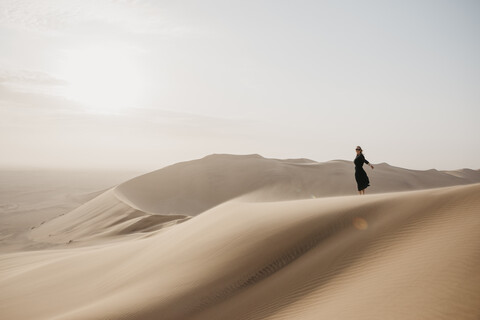 Namibia, Namib, schwarz gekleidete Frau auf Wüstendüne stehend, lizenzfreies Stockfoto