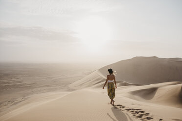 Namibia, Namib, Rückenansicht einer Frau, die barfuß auf einer Wüstendüne läuft - LHPF00260