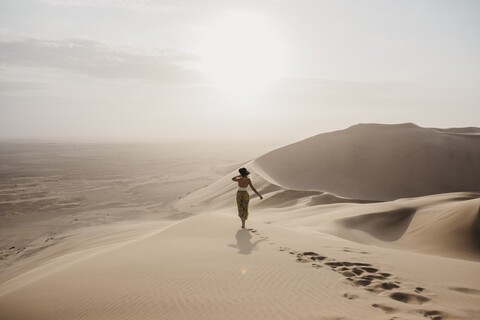 Namibia, Namib, Rückenansicht einer Frau, die auf einer Wüstendüne steht und die Aussicht betrachtet, lizenzfreies Stockfoto