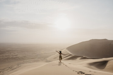 Namibia, Namib, Rückenansicht einer Frau, die auf einer Wüstendüne steht und die Aussicht betrachtet - LHPF00263