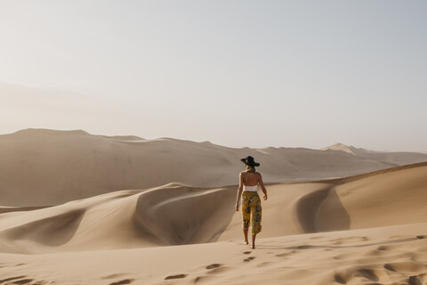 Namibia, Namib, Rückenansicht einer Frau, die barfuß auf einer Wüstendüne läuft, lizenzfreies Stockfoto