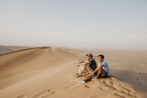 Namibia, Namib, zwei Freunde sitzen auf einer Wüstendüne und betrachten die Aussicht - LHPF00270