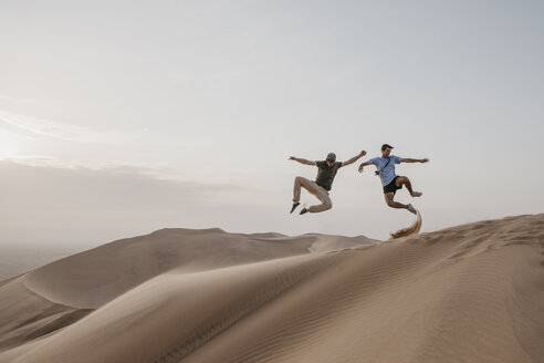 Namibia, Namib, two friends jumping in the air on desert dune - LHPF00272