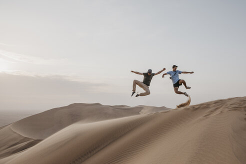 Namibia, Namib, zwei Freunde springen auf einer Wüstendüne in die Luft - LHPF00272