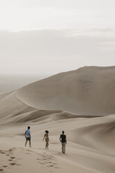 Namibia, Namib, three friends walking down desert dune - LHPF00275