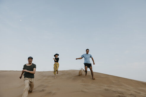 Namibia, Namib, drei Freunde rennen eine Wüstendüne hinunter und haben Spaß - LHPF00277