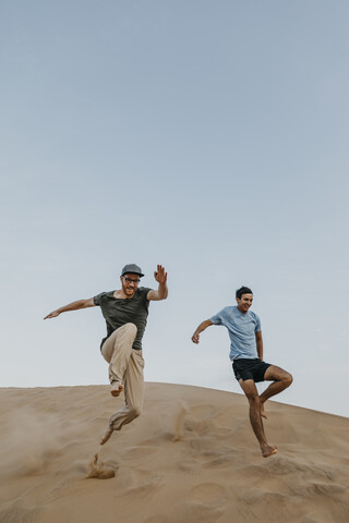 Namibia, Namib, zwei Freunde springen die Wüstendüne hinunter, lizenzfreies Stockfoto