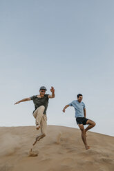 Namibia, Namib, zwei Freunde springen die Wüstendüne hinunter - LHPF00278