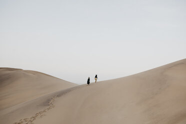 Namibia, Namib, back view of two women walking on desert dune - LHPF00279