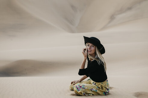 Namibia, Namib, Porträt einer modischen Frau auf einer Wüstendüne sitzend - LHPF00281