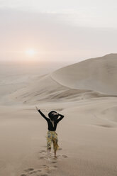 Namibia, Namib, Rückenansicht einer modischen Frau, die auf eine Wüstendüne springt - LHPF00283