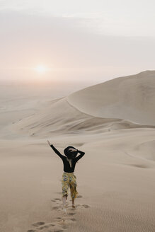 Namibia, Namib, back view of fashionable woman jumping on desert dune - LHPF00283