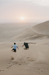 Namibia, Namib, Rückenansicht von zwei Freunden, die auf einer Wüstendüne in die Luft springen - LHPF00284
