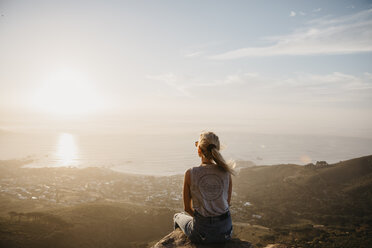 Südafrika, Kapstadt, Kloof Nek, Frau sitzt bei Sonnenuntergang auf einem Felsen - LHPF00289