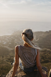 South Africa, Cape Town, Kloof Nek, woman sitting on rock at sunset - LHPF00290