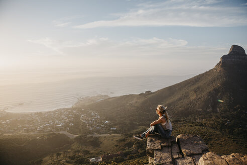 South Africa, Cape Town, Kloof Nek, woman sitting on rock at sunset - LHPF00291