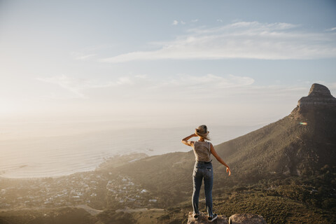 South Africa, Cape Town, Kloof Nek, woman standing on rock at sunset stock photo