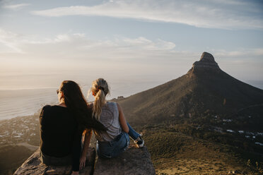 Südafrika, Kapstadt, Kloof Nek, zwei Frauen sitzen bei Sonnenuntergang auf einem Felsen - LHPF00295
