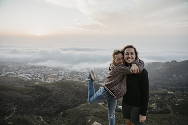 Südafrika, Kapstadt, Kloof Nek, Porträt von zwei glücklichen Frauen, die sich bei Sonnenuntergang umarmen - LHPF00305