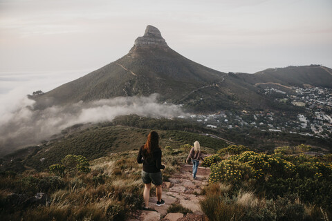 Südafrika, Kapstadt, Kloof Nek, zwei Frauen auf einem Wanderweg bei Sonnenuntergang, lizenzfreies Stockfoto