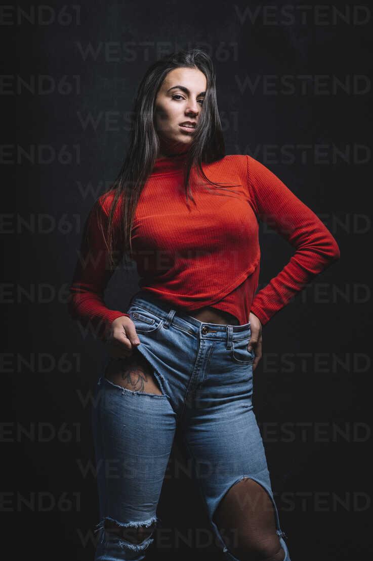 Side view of young female with bare breasts wearing casual jeans