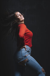 Porträt einer kurvenreichen jungen Frau, die ihr Haar vor einem schwarzen Hintergrund wirft - DAMF00015