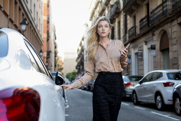 Young businesswoman with cell phone on city street - MAUF02104