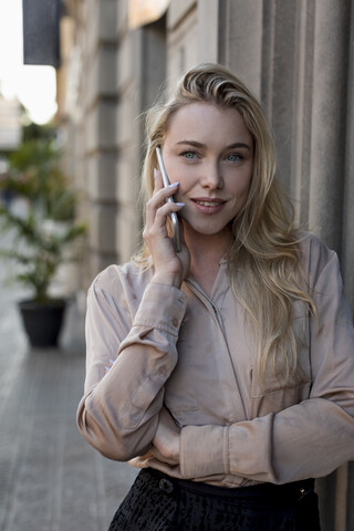 Porträt der schönen jungen Geschäftsfrau auf dem Handy in der Stadt, lizenzfreies Stockfoto