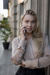 Porträt der schönen jungen Geschäftsfrau auf dem Handy in der Stadt - MAUF02107