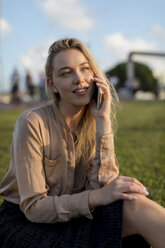 Smiling young businesswoman on cell phone on a meadow - MAUF02118
