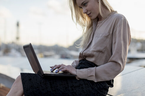 Junge Geschäftsfrau mit Laptop an der Waterfront - MAUF02124