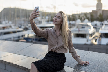 Lächelnde junge Frau macht ein Selfie am Wasser - MAUF02128