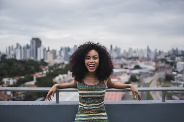 Panama, Panama City, portrait of laughing young woman on balcony - KKAF03098