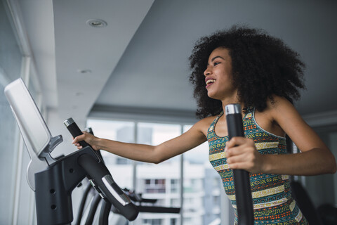 Lächelnde junge Frau auf dem Stepper im Fitnessstudio, lizenzfreies Stockfoto