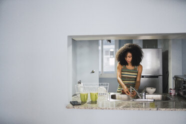 Junge Frau am Spülbecken in ihrer modernen Küche - KKAF03105