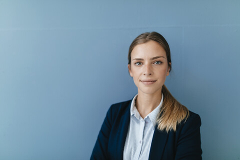 Portrait of a young businesswoman against blue background stock photo