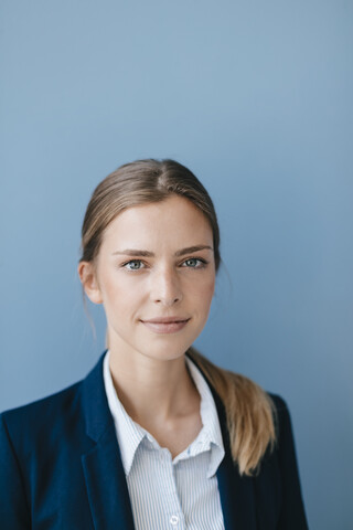 Porträt einer jungen Geschäftsfrau vor blauem Hintergrund, lizenzfreies Stockfoto