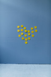 Heart-shape on a blue wall, made of yellow sticky notes - GUSF01722