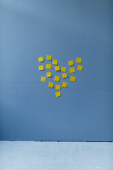 Herzform auf einer blauen Wand, aus gelben Haftnotizen - GUSF01722