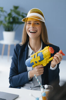 Lachende, junge Geschäftsfrau, mit Wasserpistole - GUSF01737