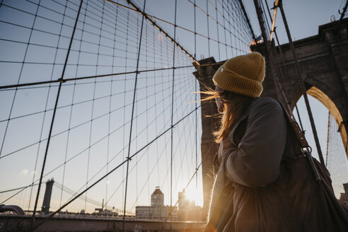 USA, New York, New York City, female tourist on Brooklyn Bridge at sunrise - LHPF00323