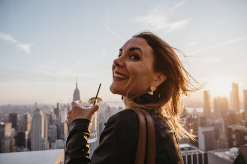 USA, New York, New York City, Frau mit Cocktailglas auf Aussichtspunkt bei Sonnenaufgang - LHPF00333