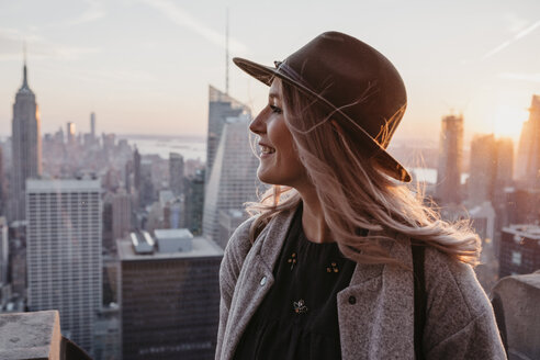 USA, New York, New York City, Porträt einer blonden Frau mit Hut bei Sonnenaufgang - LHPF00336