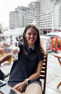 Junge schöne Frau, die mit ihren Freunden auf einer Terrasse anstößt - MGOF03887